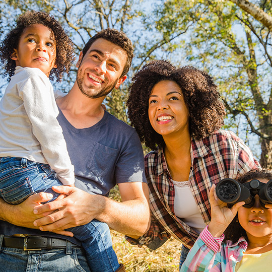 Uma família com duas crianças pequenas observam algo no horizonte com alegria