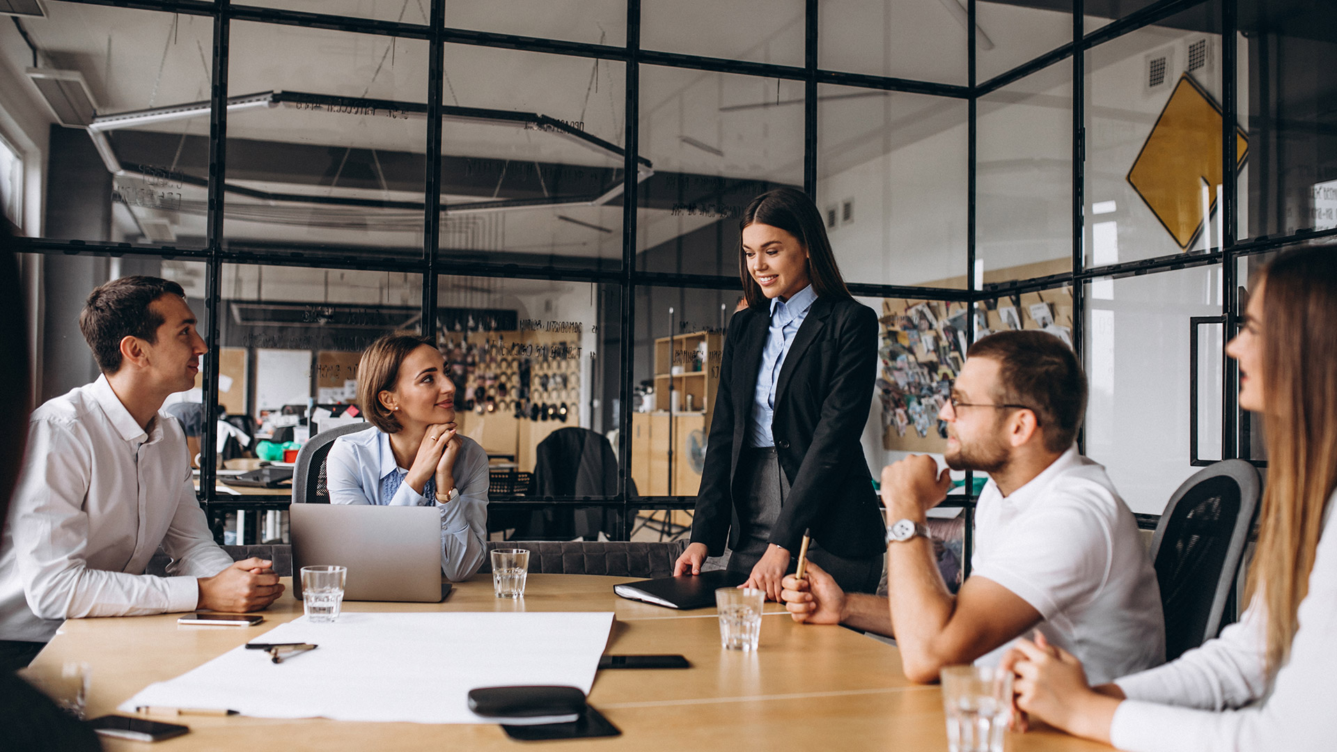 Grupo de profissionais em reunião corporativa ao redor de uma mesa de escritório, representando o planejamento de benefícios e plano empresarial.